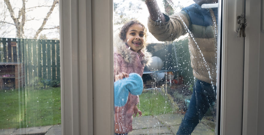 Daughter helping her father playing with water while cleaning their home windows.
