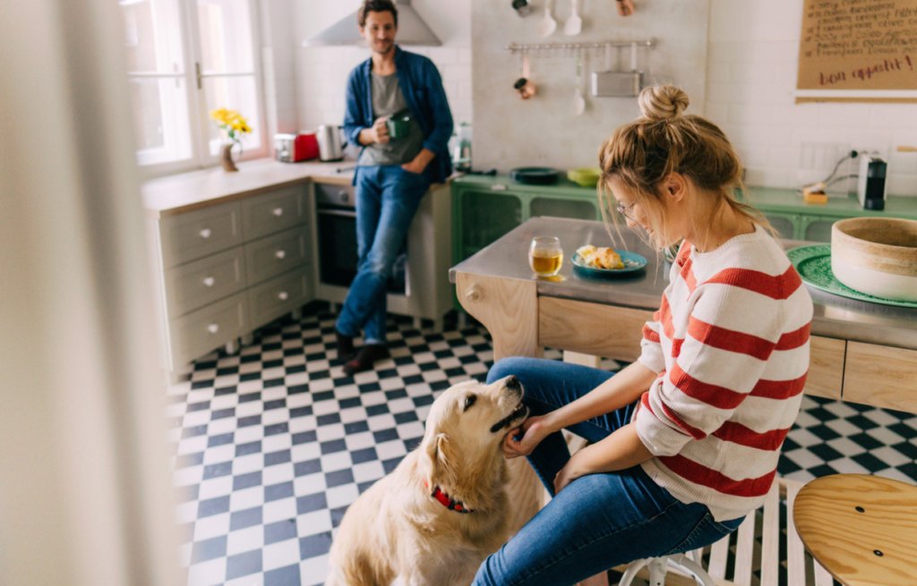 Young couple relaxing in a modern kitchen with their dog sat in front of the women. 