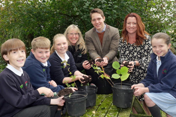 Image of school students and Hinckley & Rugby Building Society colleagues holding tree saplings.