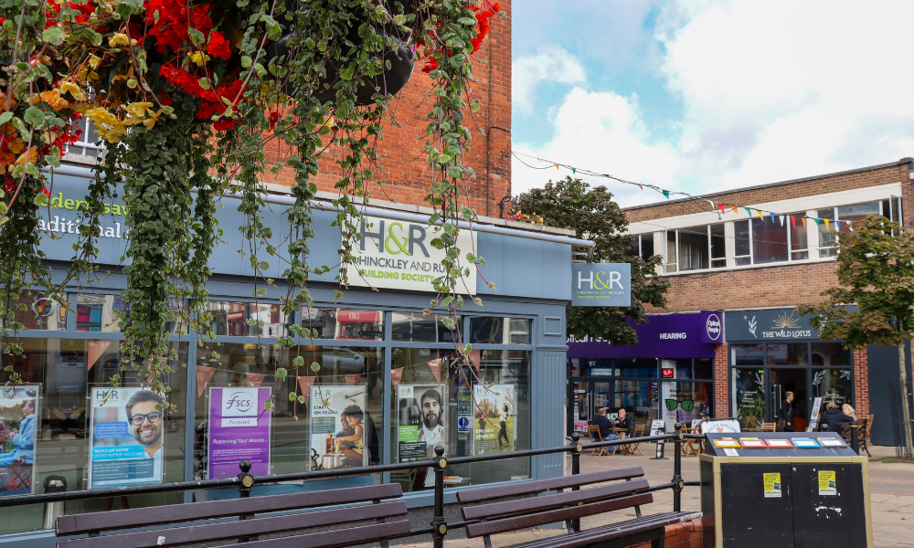 Image of Hinckley & Rugby Building Society Castle Street Branch on a bright day with a elevated flower pot in the foreground.